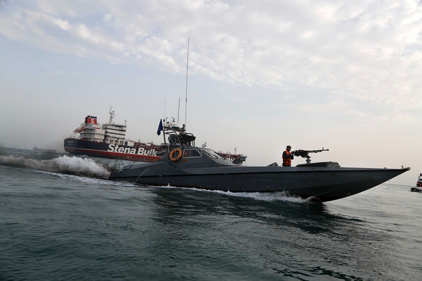 An Iranian speedboat with a machine gunner on the front moves around a British-flagged oil tanker.