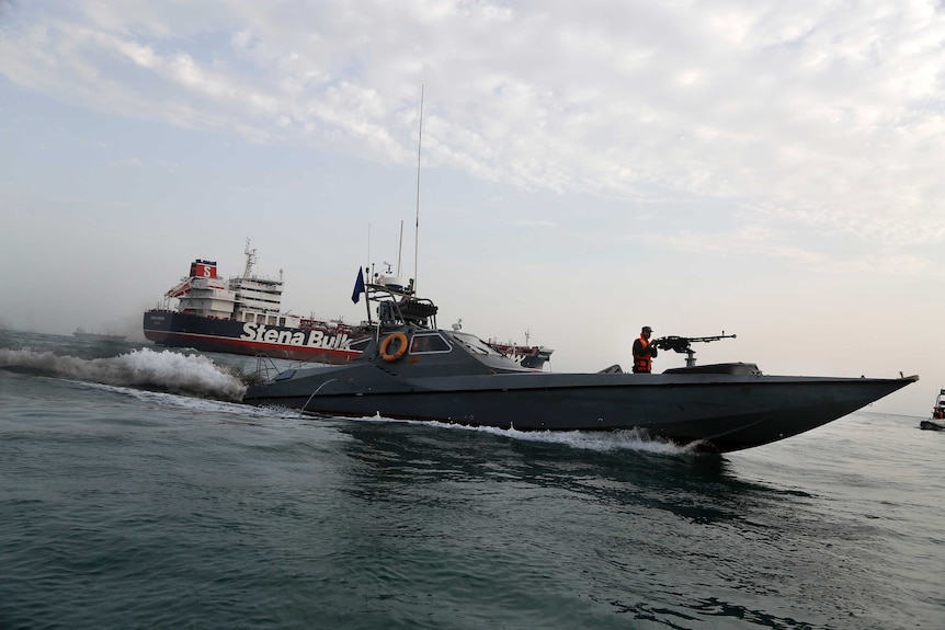 An Iranian speedboat with a machine gunner on the front moves around a British-flagged oil tanker.