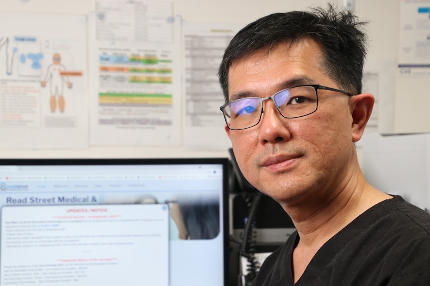 Dr Wee sits at a computer with medical diagrams in the background.