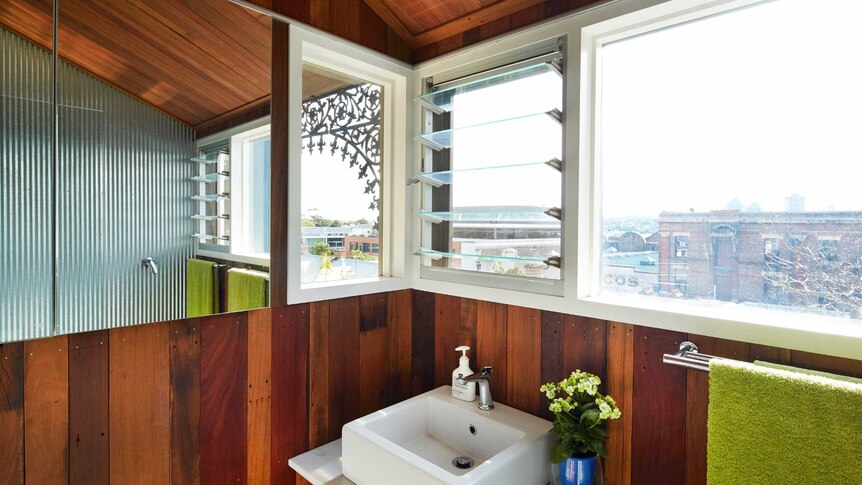 A bathroom vanity and mirror, window looking out to urban area