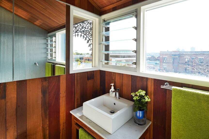 A bathroom vanity and mirror, window looking out to urban area