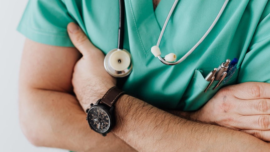 Man with folder arms with a stethoscope around his neck