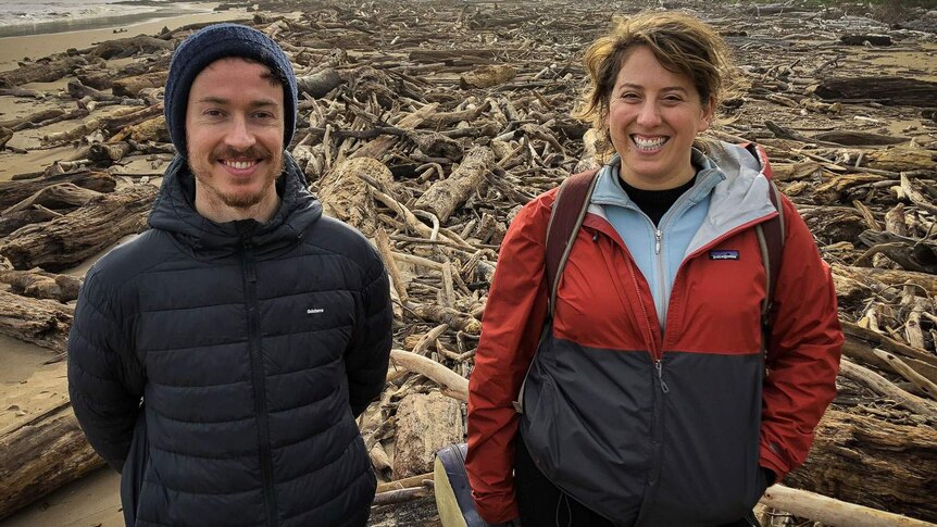 Joseph Franklin and Rachel Meyers smiling in a massive field of driftwood