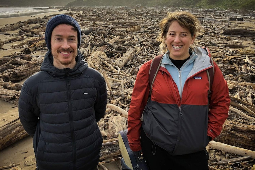 Joseph Franklin and Rachel Meyers smiling in a massive field of driftwood