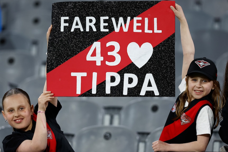 Essendon Bombers fans hold up a sign reading "Farewell 43 Tippa" for Anthony McDonald-Tipungwuti.