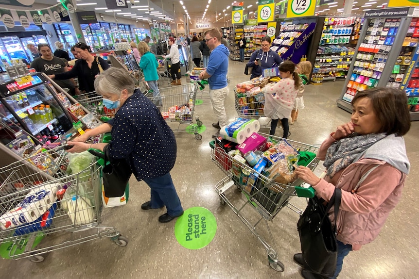 People standing with trolleys at a supermarket