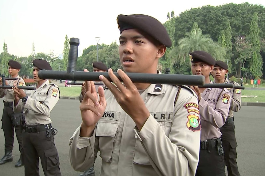 Jakarta policeman holds baton during drill.