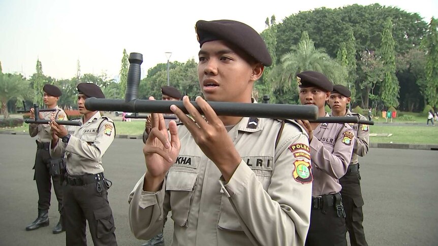 Jakarta policeman holds baton during drill.