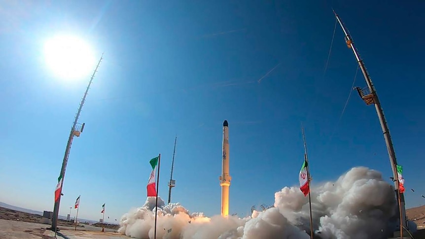 A satellite carrier rocket takes off among Iran flags