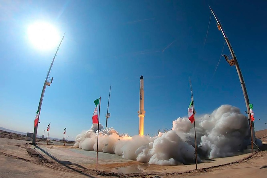 A satellite carrier rocket takes off among Iran flags