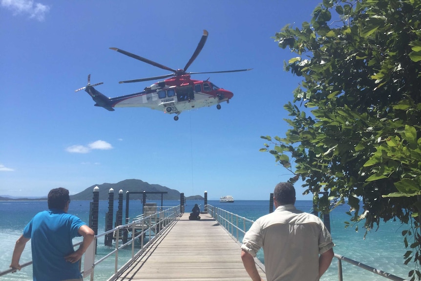 A rescue helicopter with a winch down off a jetty at Fitzroy Island.