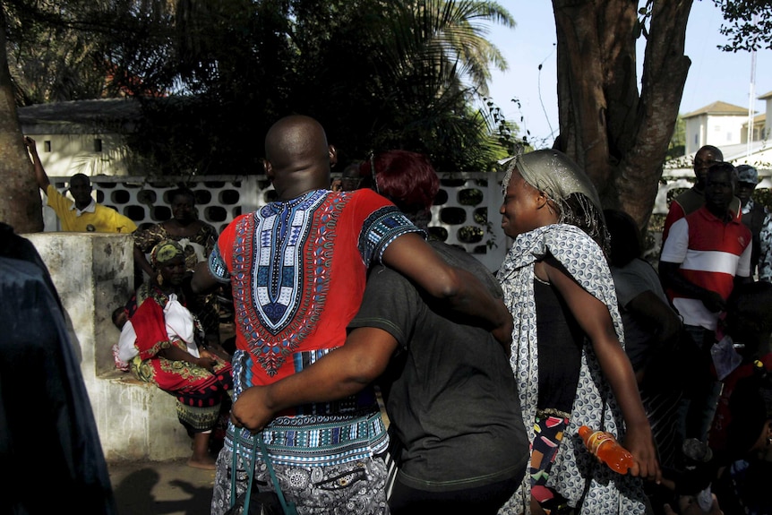 People comfort each other in Bassam, Ivory Coast.