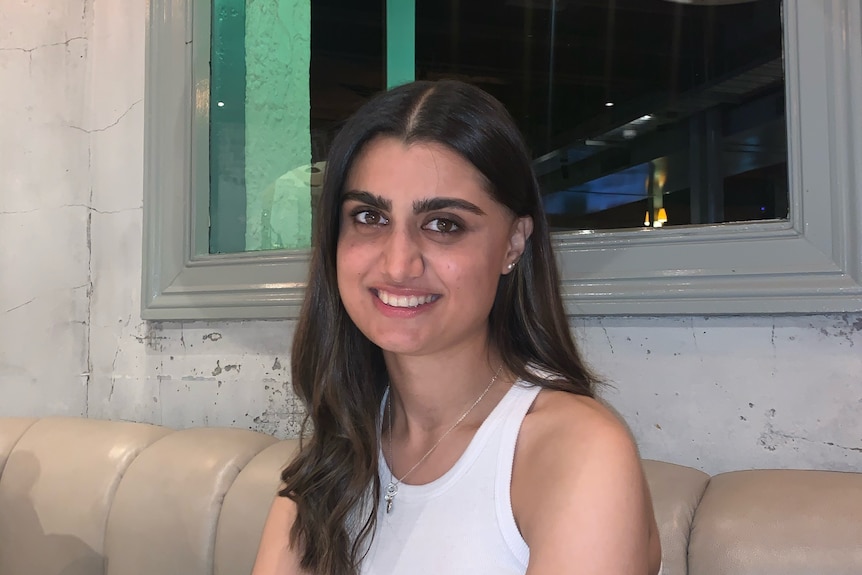 A woman smiling in a white top.