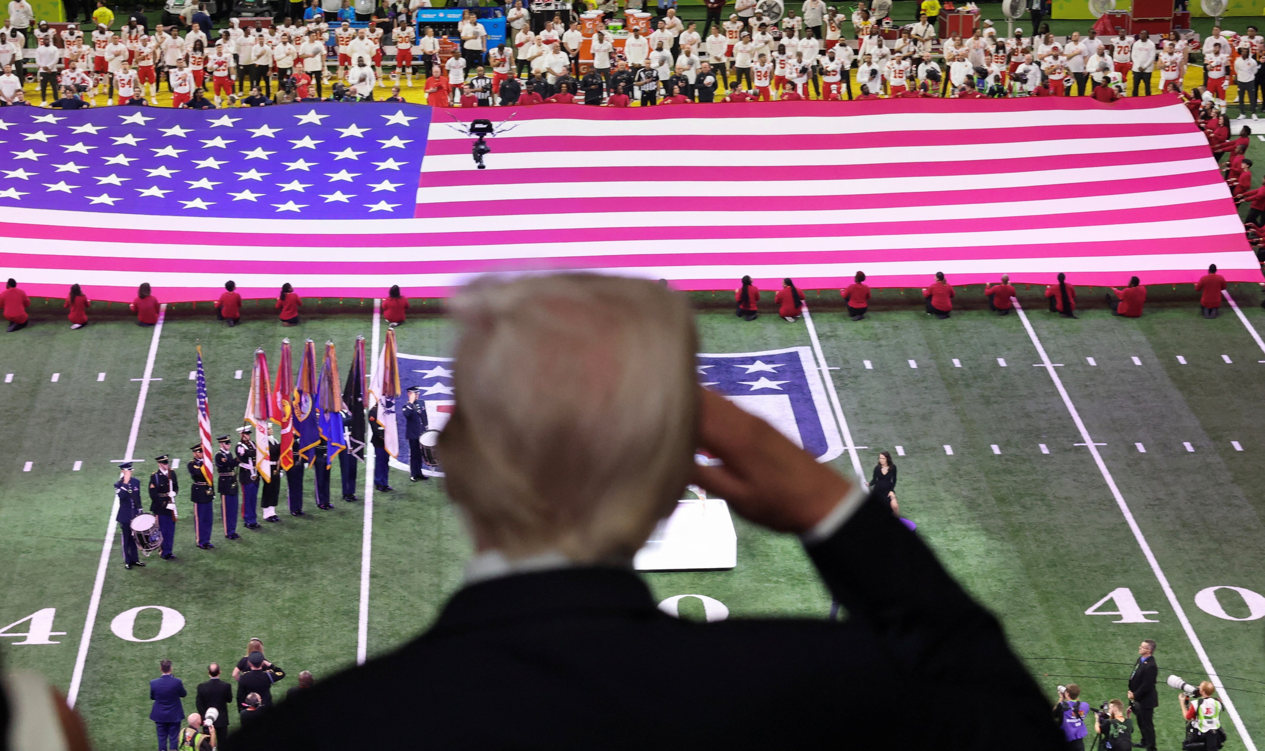 Trump salutes as a flag is brought onto the Super Bowl pitch