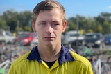 A young man in a high vis shirt looks at the camera