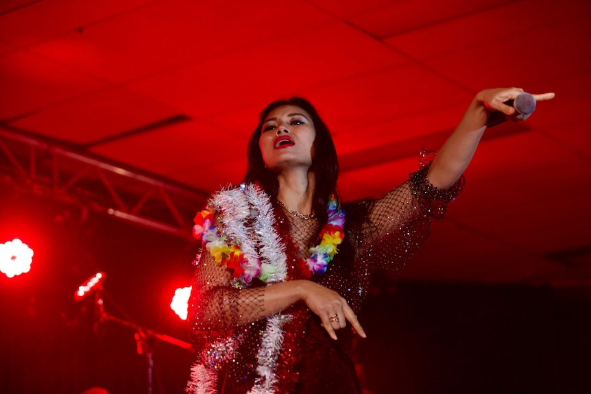 A woman performing on stage points at the crowd. 