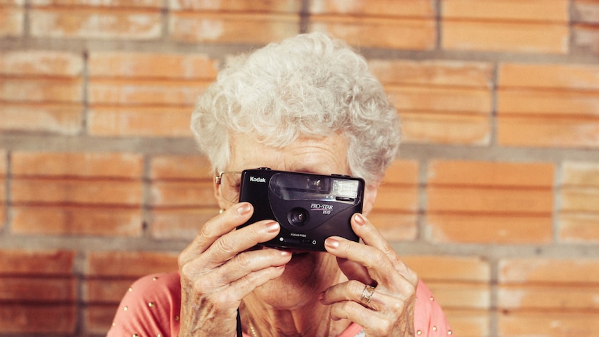 Elderly woman holding a camera.