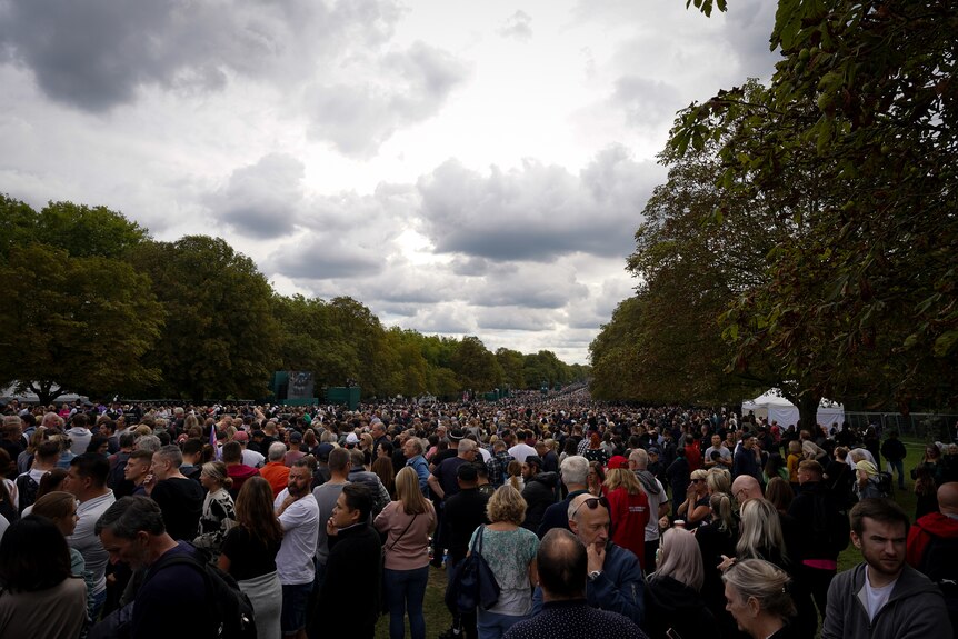 A crowd of thousands of people gathered under a grey sky,