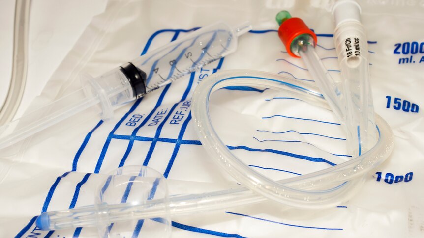 Photo of urinary catheter spread out on an empty plastic collection bag.