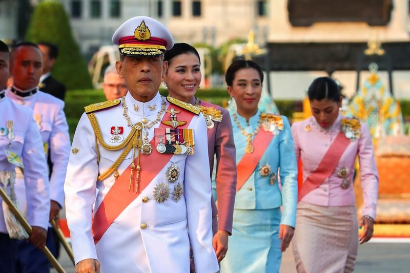 Thailand's King Maha Vajiralongkorn walking in a traditional white uniform during a parade.