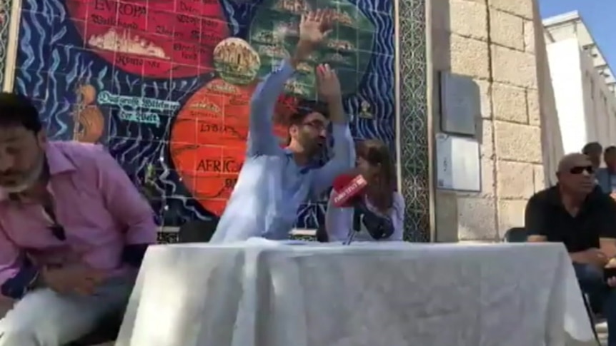 Aziz Abu Sarah raises his hands to protect himself from protesters pelting him with eggs.