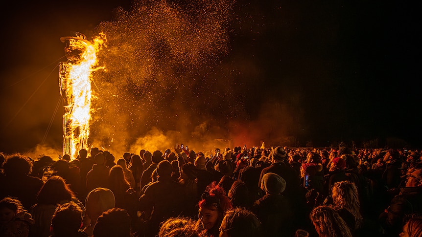Crowd watches large effigy burning at pagan festival.