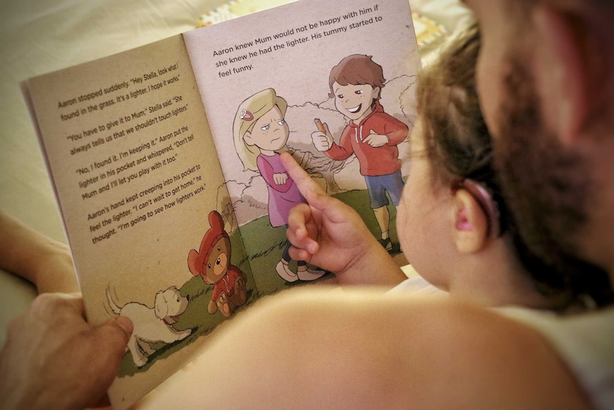 A man reading a children's book to a small girl.