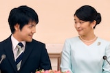Kei Komuro, wearing a suit, gazes at his fiance, Princess Mako, who is wearing a light blue top.