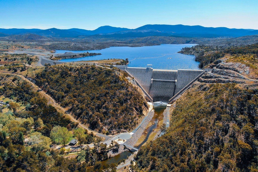 An aerial shot looks over a well-filled dam reservoir.