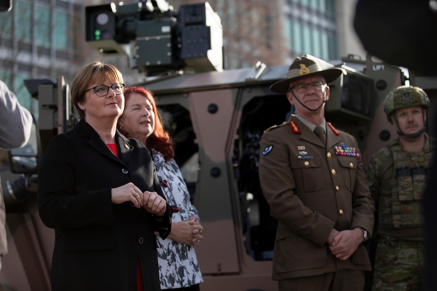 Linda Reynolds, Melissa Price and Rick Burr stand in front of a Hawkei