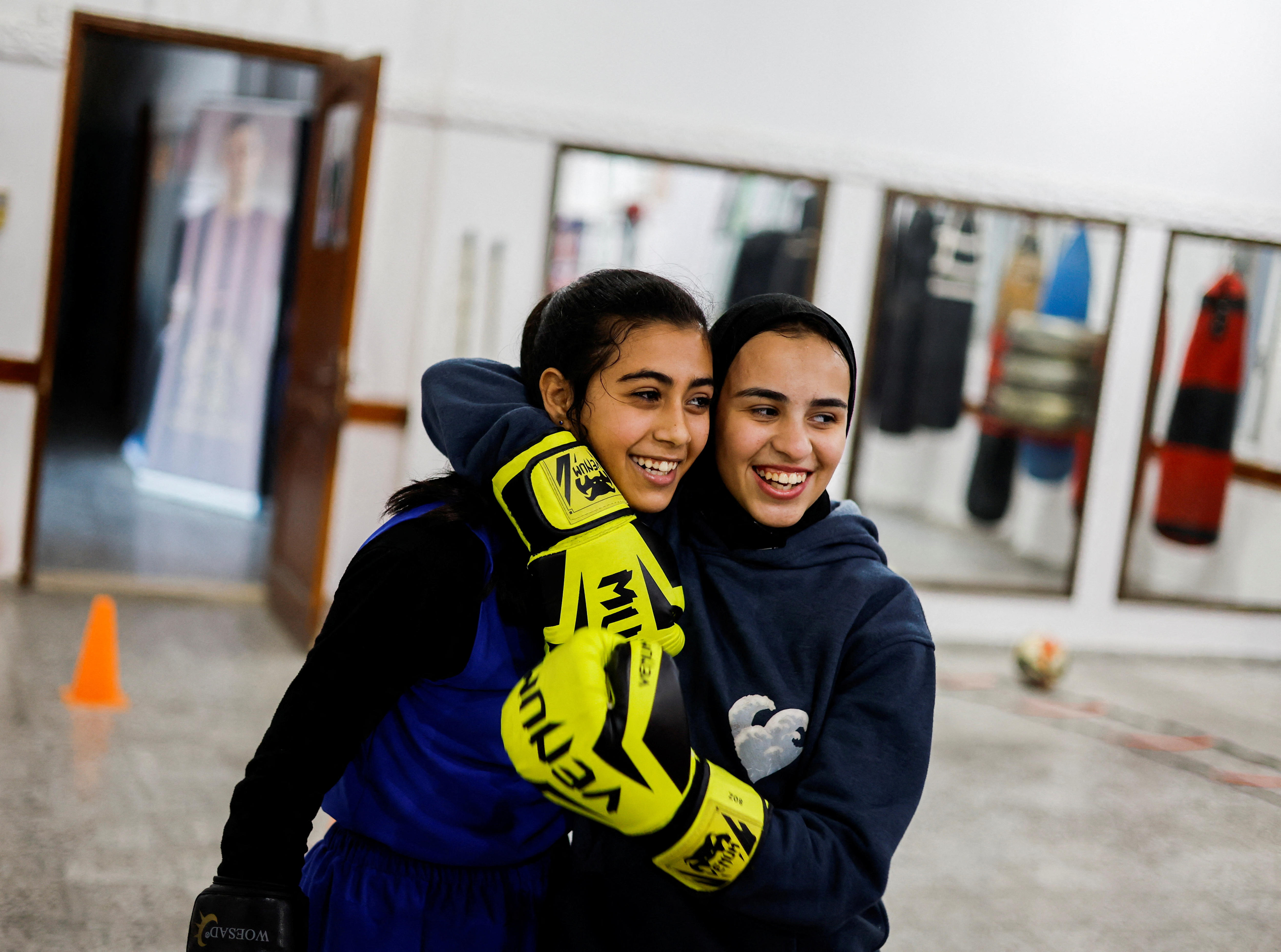 Two girls stand next to eachother, with their arms around eachother. 