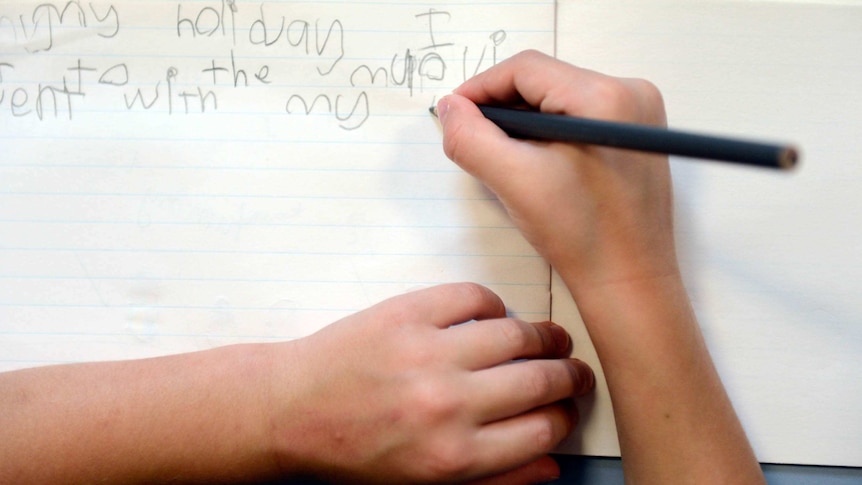 An overhead shot shows a young child writing in an exercise book