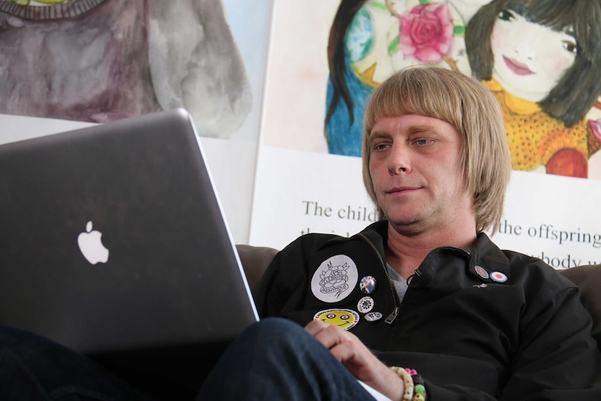 A man sits on a couch with a laptop