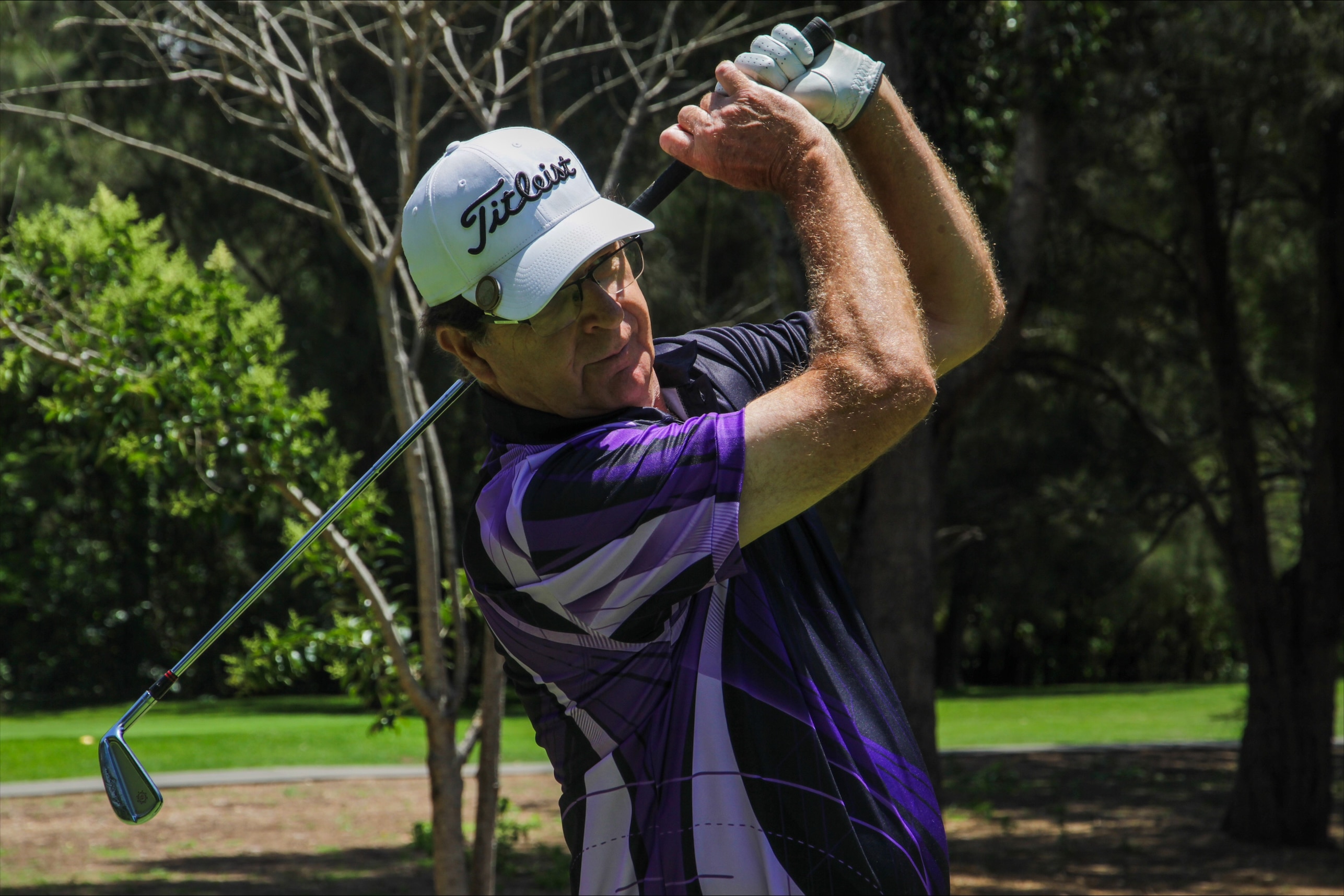 A man poses after swinging a golf club.