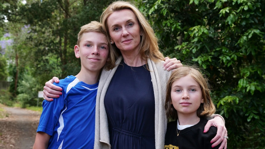 A woman and two kids looking into the camera