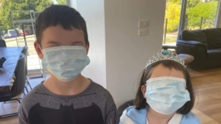 Two children wearing oversized paper respiratory masks.