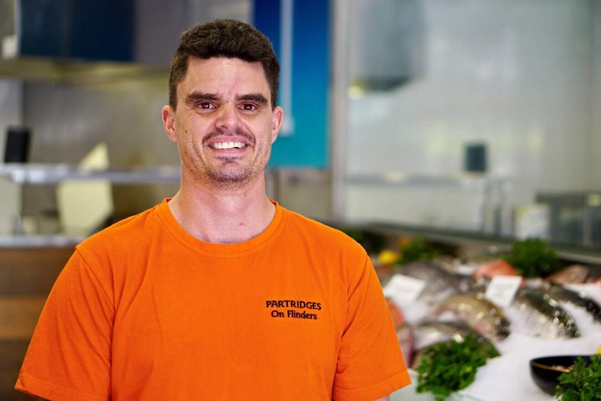 Brown-haired man standing in seafood shop.