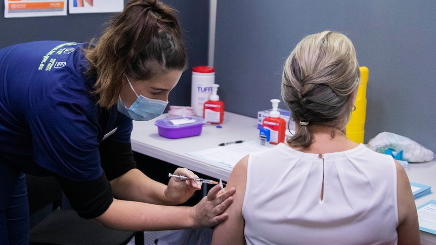 Nurse giving vaccine to female patient.