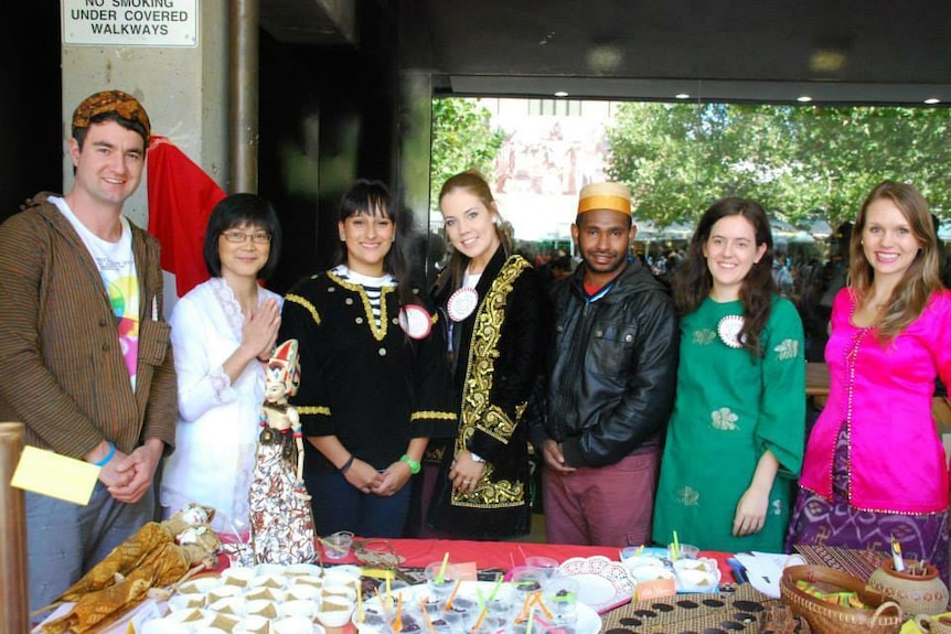 A group of people standing together and some of them wearing Indonesian traditional clothes.