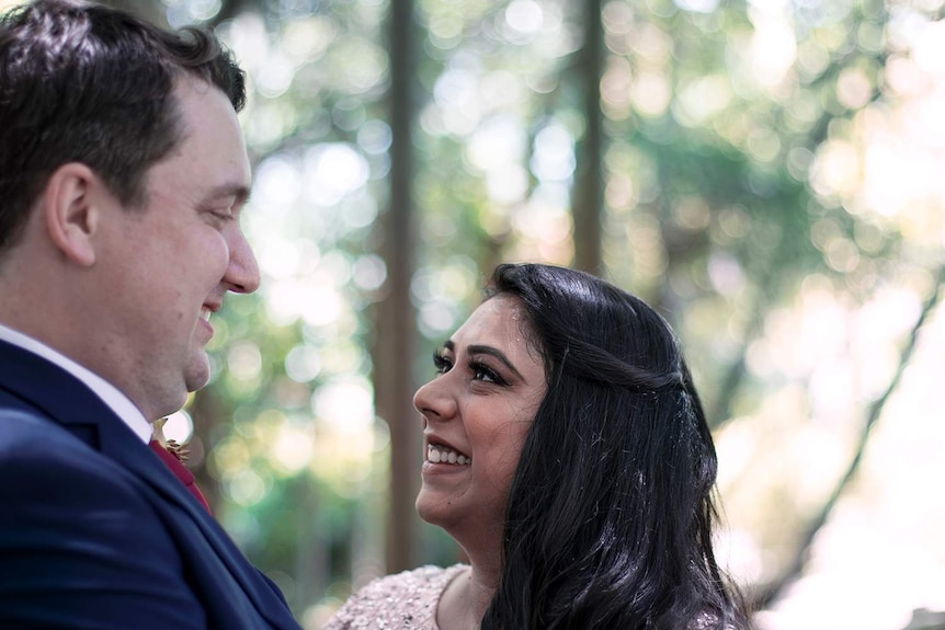 Couple Ruby and Matt smile at each other during their wedding ceremony.