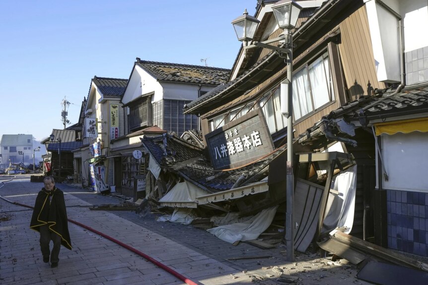 A man walks next to a row of destroyed houses after an earthquake