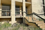 Stairs lead to cut ring lock fencing and smashed windows.