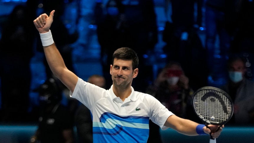 Novak Djokovic raises his arm above his head with his thumb raised