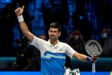 Novak Djokovic raises his arm above his head with his thumb raised