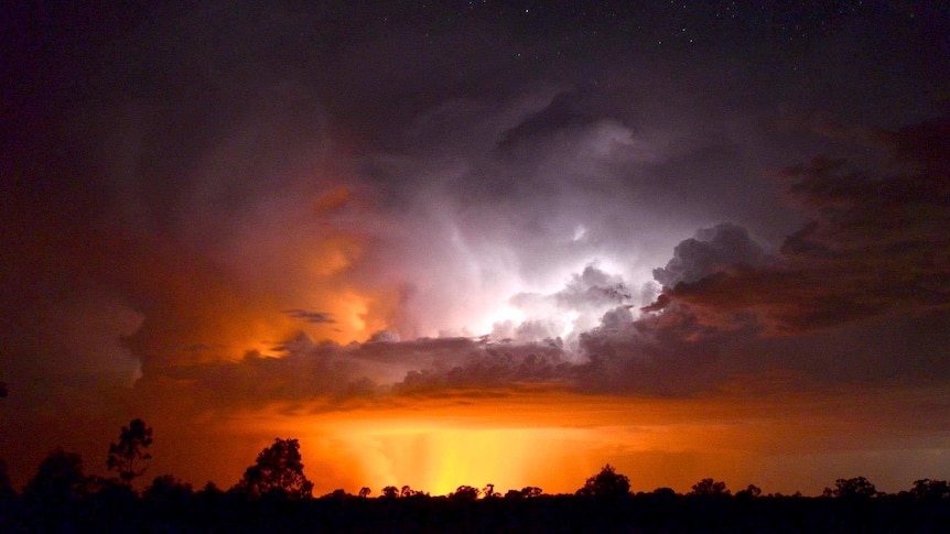 Glow from bushfire lights up storm cloud.