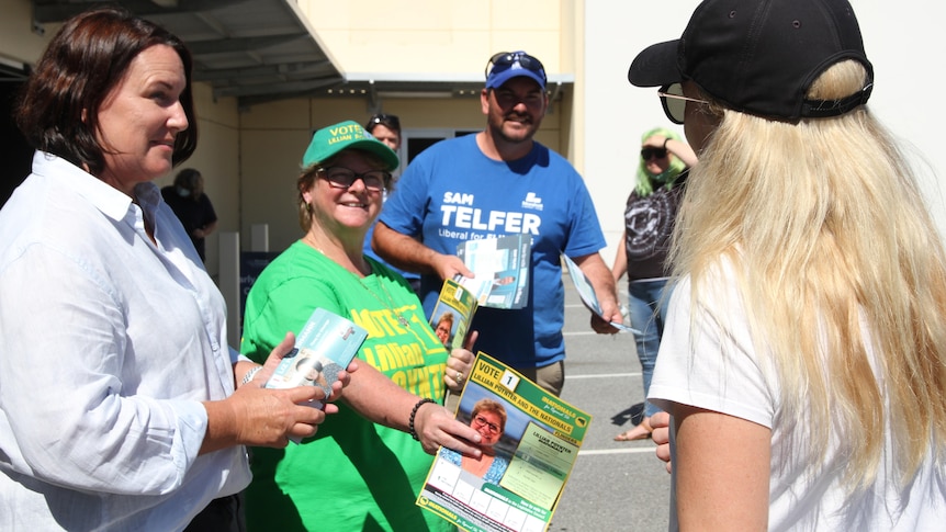 Three election candidates talking to a blonde woman. 