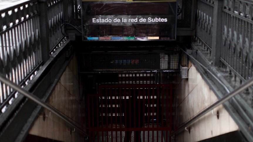 Spanish test over a stairway leading to an underground train platform in the dark