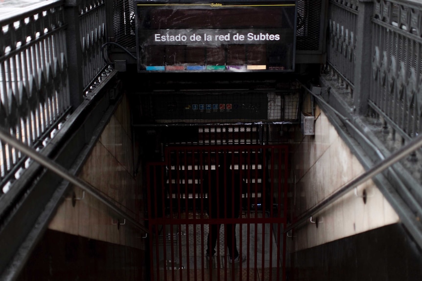 Spanish test over a stairway leading to an underground train platform in the dark