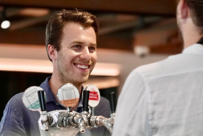 Solotel chief executive Elliot Solomon talks to a bar tender in front of beer taps.