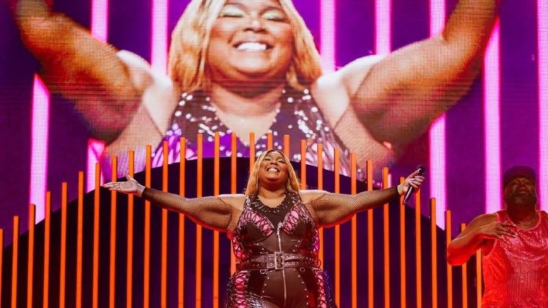 Lizzo stands with her arms outstretched and smiles on stage at Splendour in the Grass.